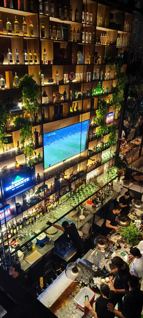Interior del Boteco Belmonte en Ipanema con pantalla gigante de fútbol y barra de bar.