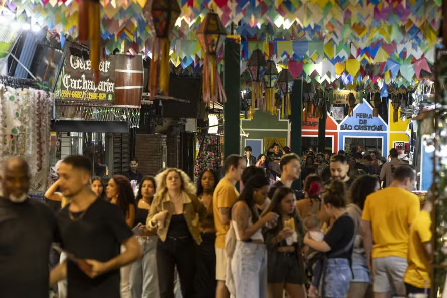 Pasillo concurrido de la Feira São Cristóvão en Río de Janeiro con puestos de cachaça artesanal y decoración típica de banderines.