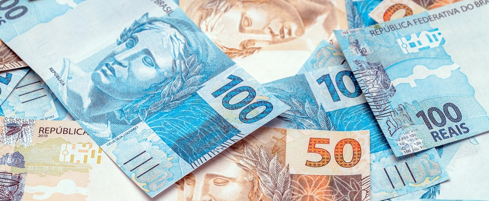 Varios billetes de reales brasileños de 100, 50 y 10 unidades sobre una mesa, moneda oficial de Brasil.