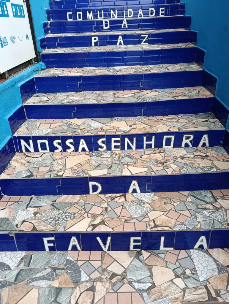 Primer plano de escaleras de mosaico azul en la favela de Vidigal con las frases "Comunidade da Paz" y "Nossa Senhora da Favela" escritas en los peldaños en Río de Janeiro.