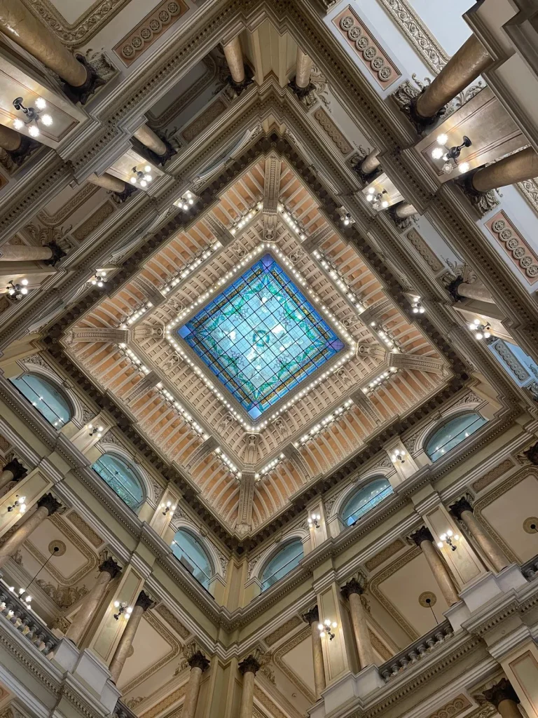 Vista en contrapicado de los detalles arquitectónicos del techo neoclásico interior de la Biblioteca Nacional de Brasil, mostrando la estructura de hierro y cristal de la cúpula.