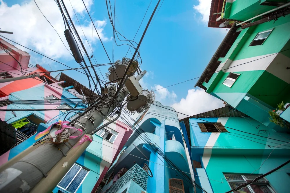 Casas de colores apiladas en la ladera de una favela de Río de Janeiro con la vegetación del morro de fondo.